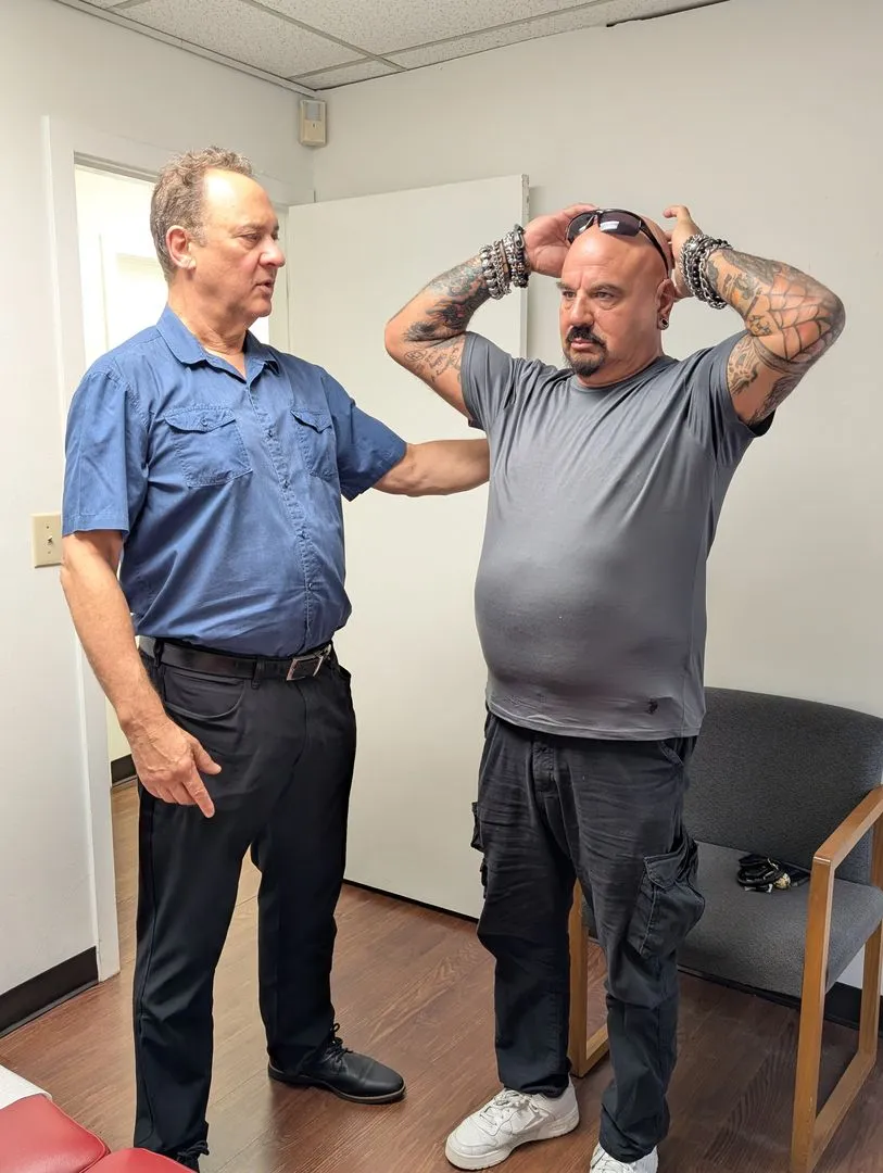 Dr. Leonard Fox evaluating a patient's shoulder movement during a consultation at Georgetown Chiropractic